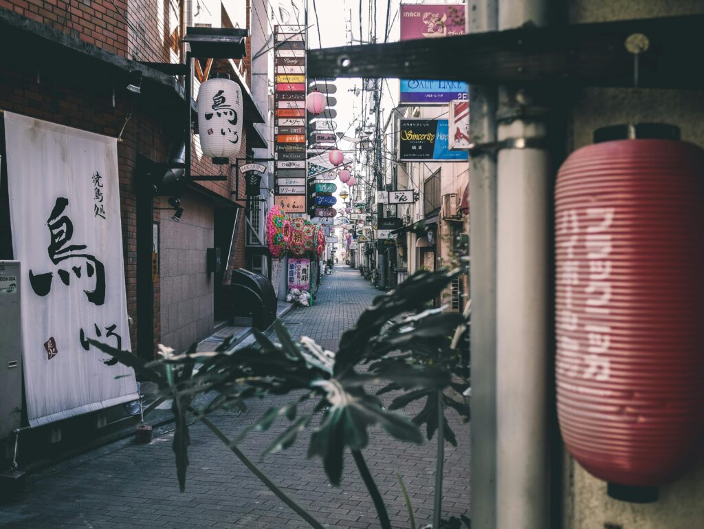A picturesque alleyway adorned with traditional lanterns and vibrant signage captures urban Japanese culture.