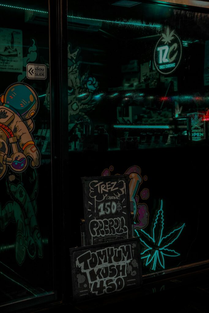 A neon-lit cannabis dispensary with artistic window designs captured at night.