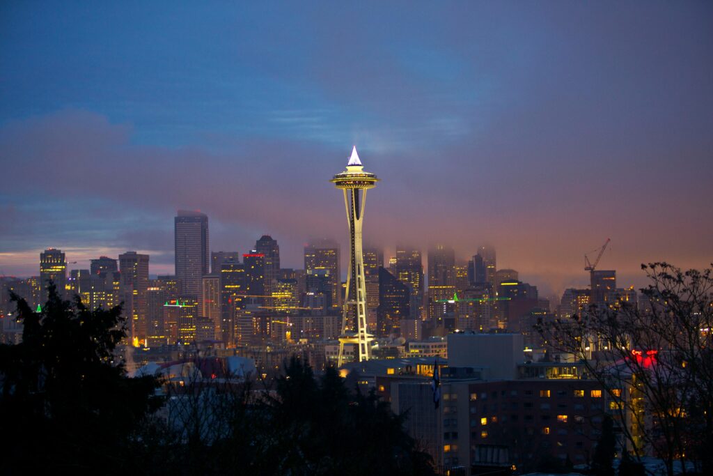 Illuminated Space Needle and Seattle cityscape during twilight.