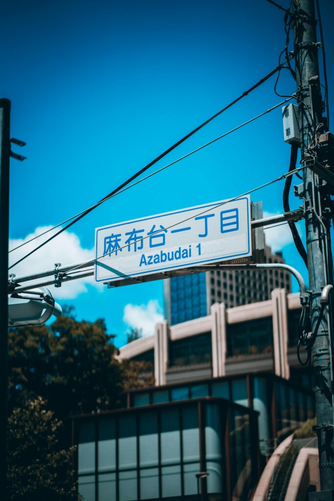 A vibrant street sign in Azabudai, Tokyo with modern urban buildings in the background.