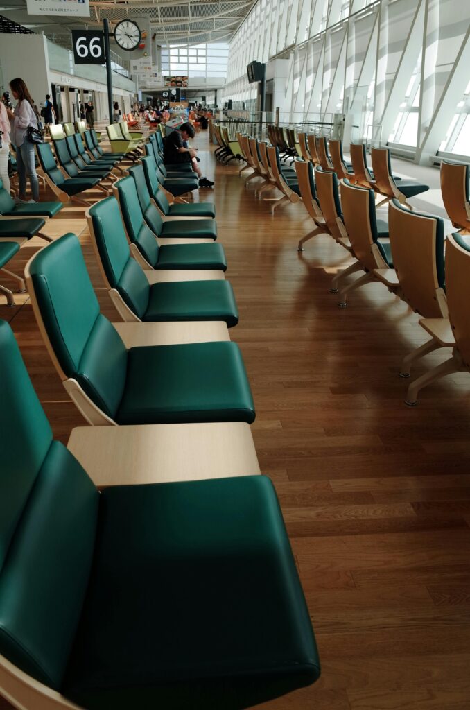 Spacious airport waiting area with green cushioned chairs and natural lighting at Hokkaido's New Chitose Airport.