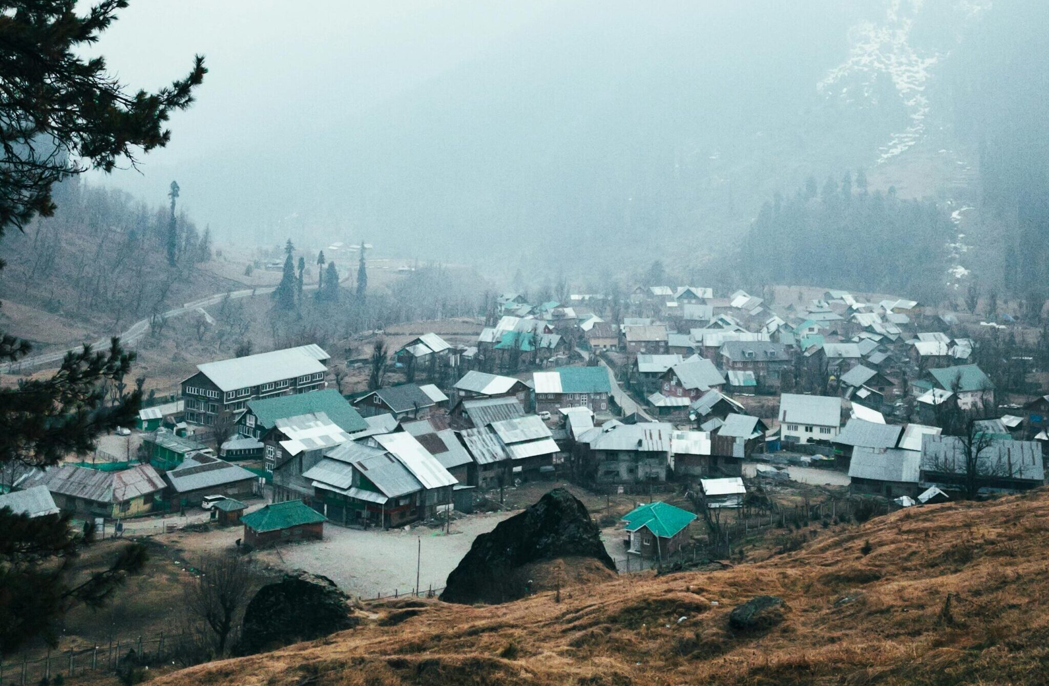 Discover the tranquil charm of Pahalgam village nestled in misty mountains, capturing serene landscapes and rustic rooftops.