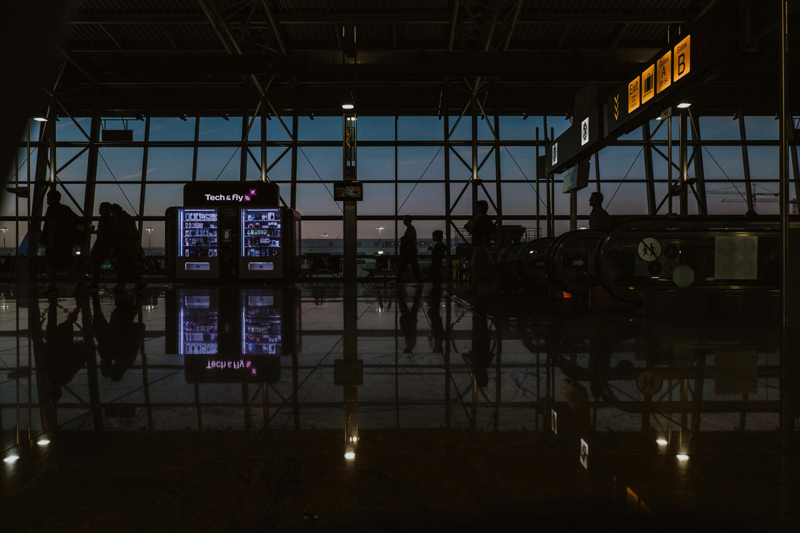 Silhouettes and reflections inside Brussels Zaventem Airport during twilight.