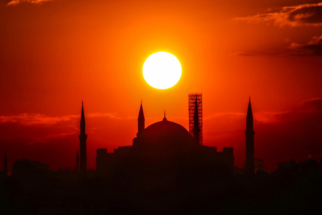 A breathtaking sunset highlights the silhouette of Hagia Sophia, Istanbul, with vivid orange hues.