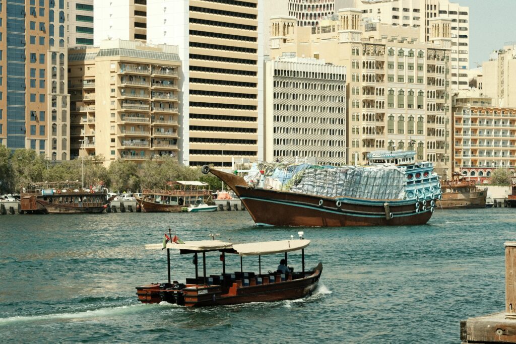 Traditional wooden boats at Dubai Creek with city skyline in the background.