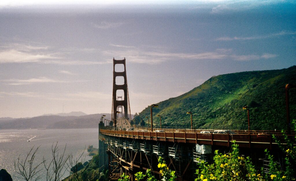 View of the iconic Golden Gate Bridge in San Francisco with lush green hills and blue sky.