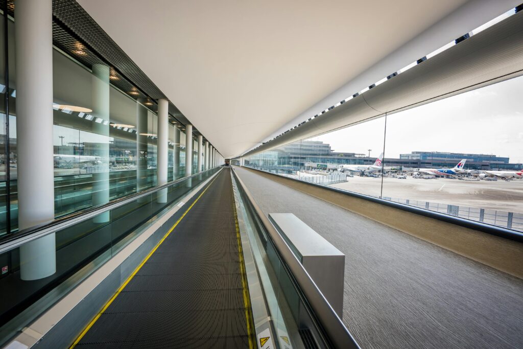 Sleek interior view of a Japanese airport terminal with a moving walkway and airplanes visible outside.