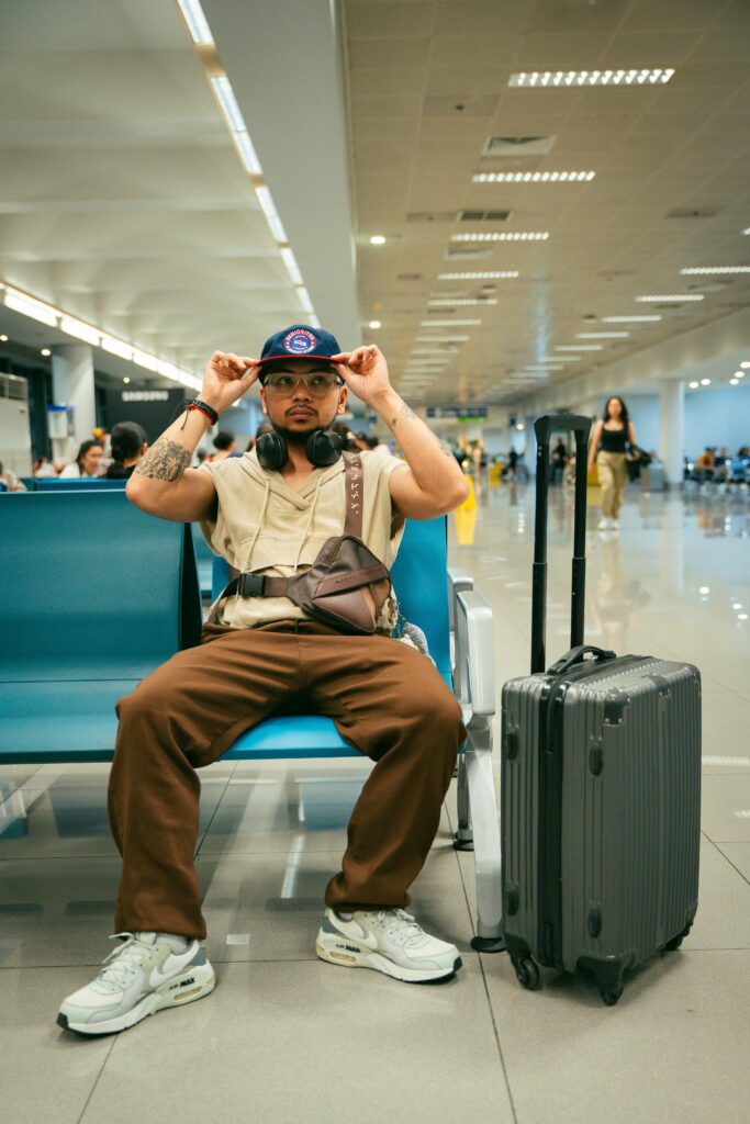 Casual traveler sitting in airport terminal with suitcase, ready for departure.