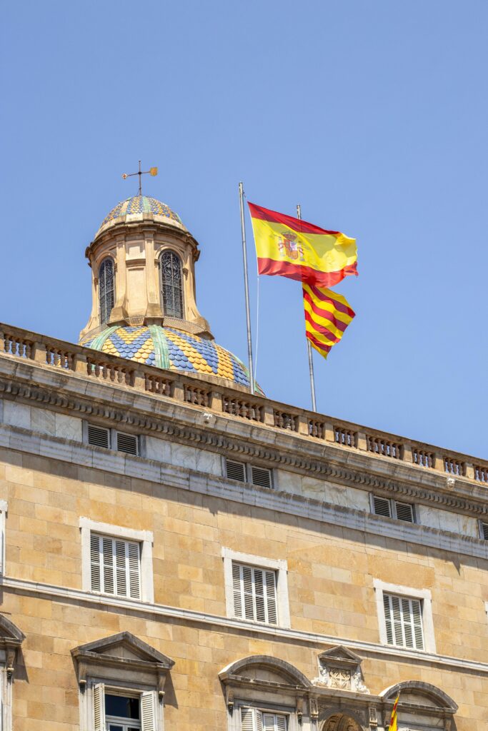Colorful dome with Spanish and Catalan flags on a historic building in Barcelona.