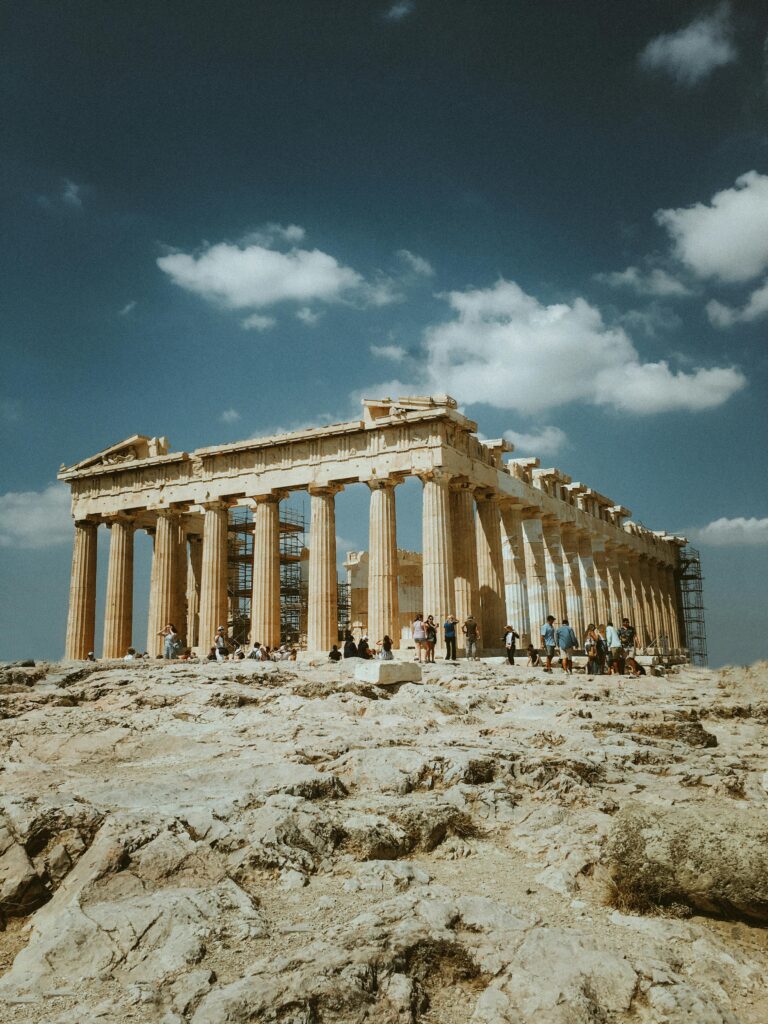 Low angle shot of the Parthenon, Athens, with tourists against a clear blue sky.