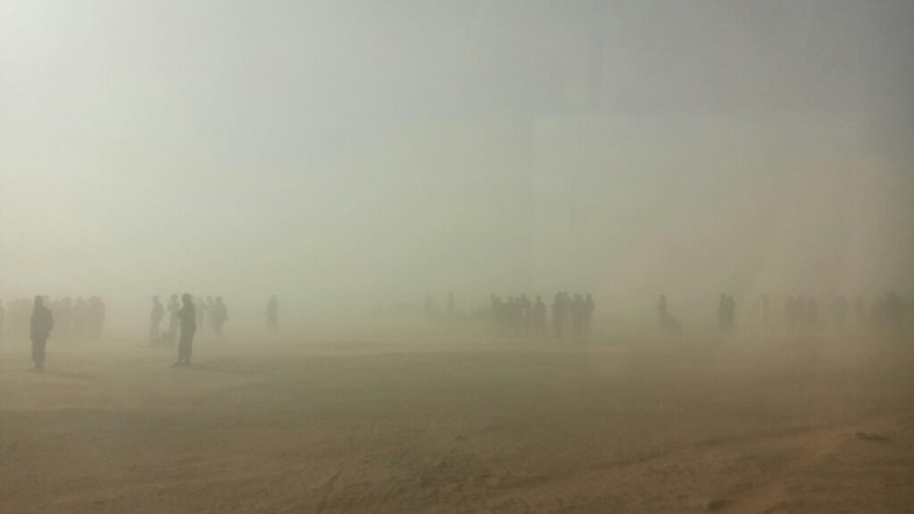 Atmospheric scene with silhouettes amidst sand and dust in Tindouf, Algeria.