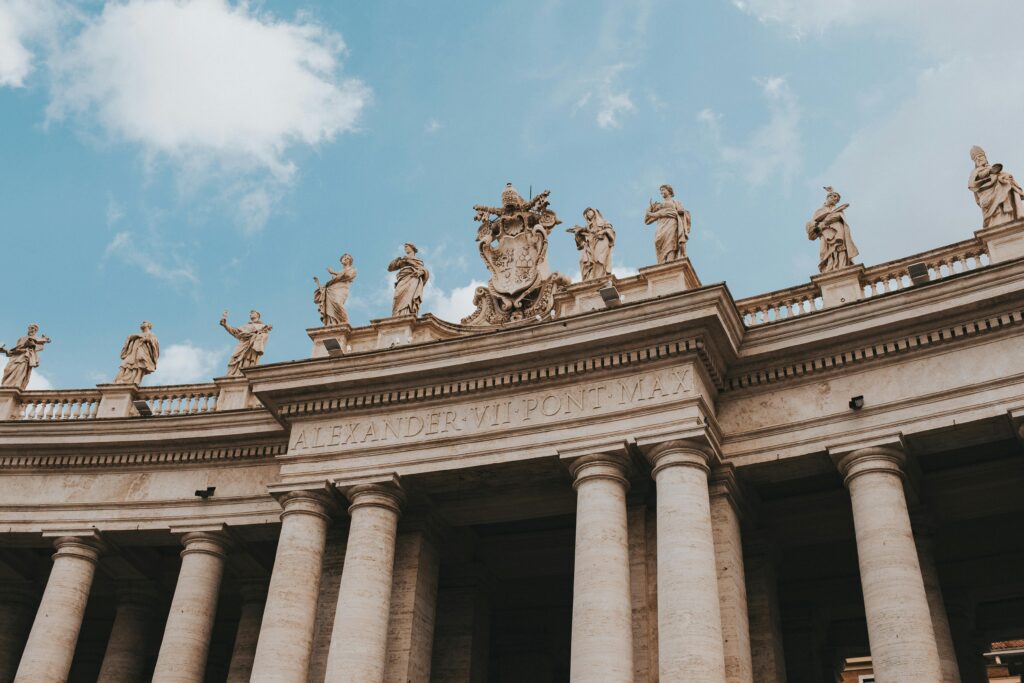 Low angle view of St. Peter's Square colonnade with clear blue sky and statues.