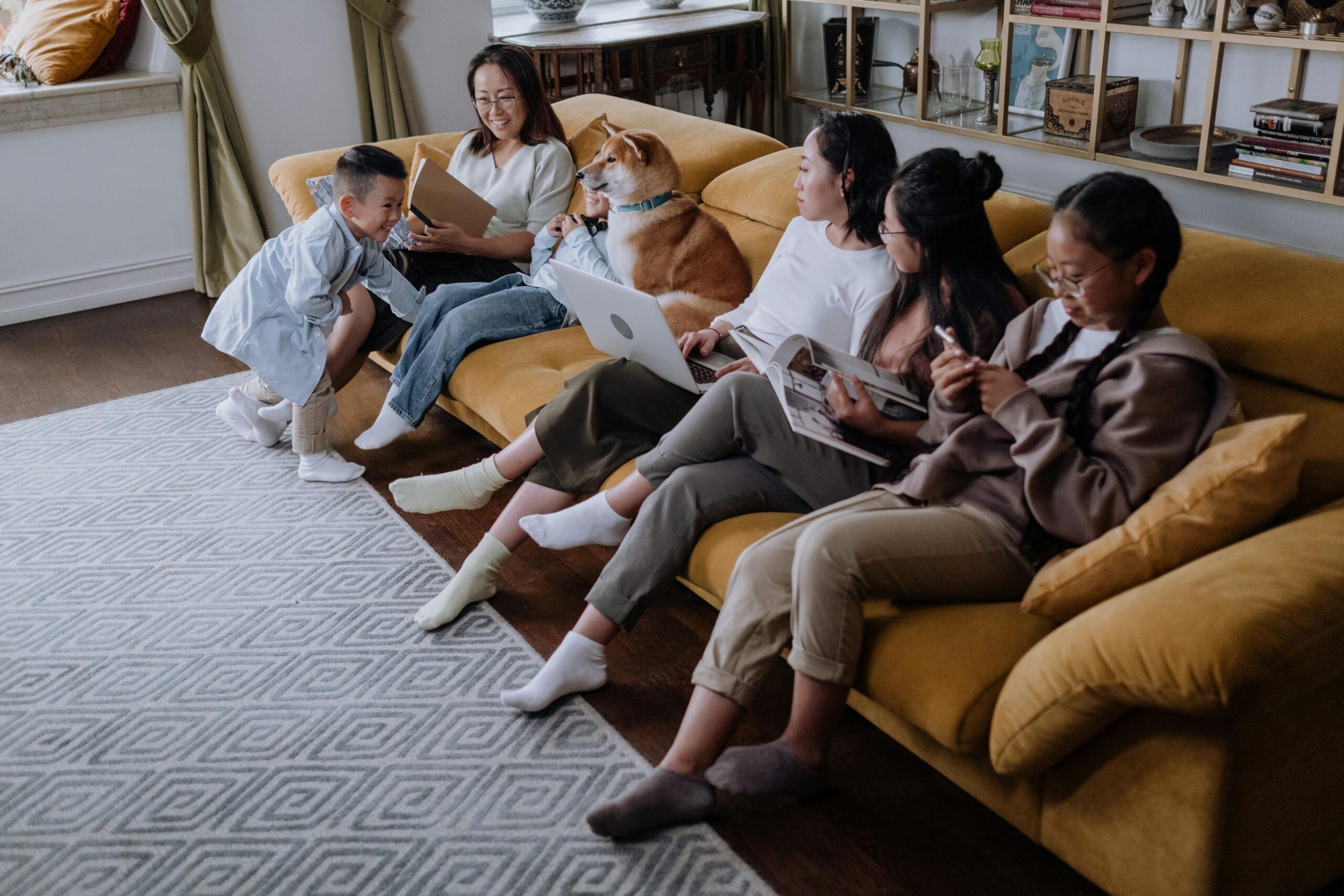 An East Asian family bonding with their pet Shiba Inu in a cozy living room setting.
