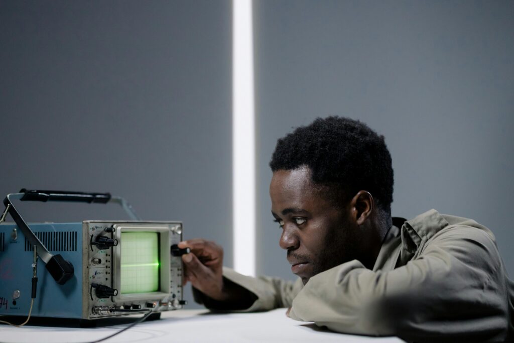 Focused man examining oscilloscope signal in a studio setting.