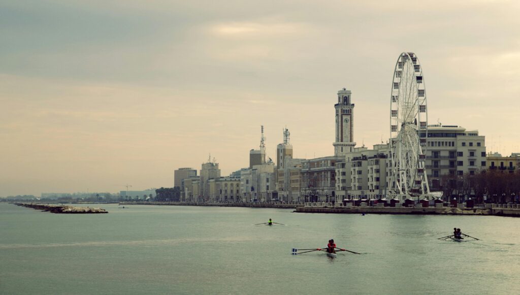 Serene view of a riverside cityscape with rowing boats and a prominent ferris wheel.