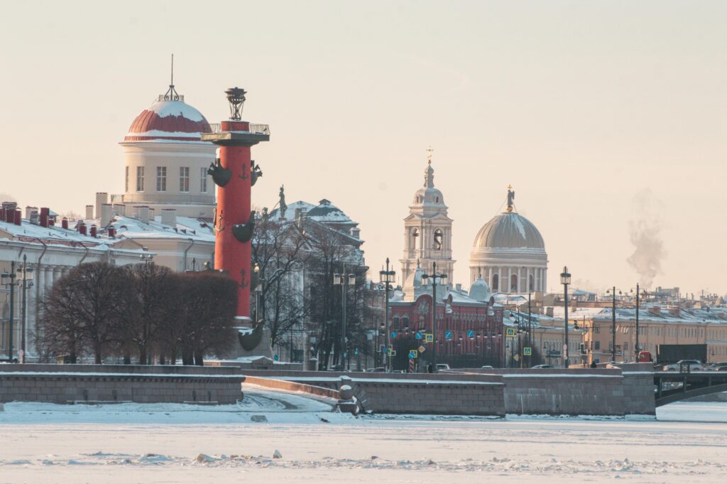 A stunning winter view of St. Petersburg featuring the historic Rostral Columns surrounded by snow.