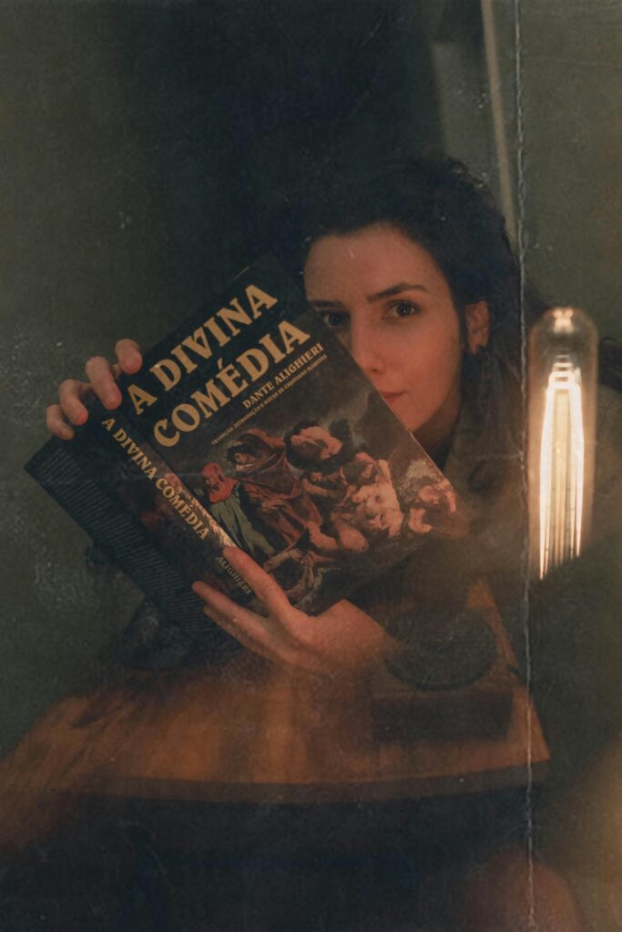 Portrait of a woman holding 'A Divina Comédia' in a São Paulo café, Brazil.
