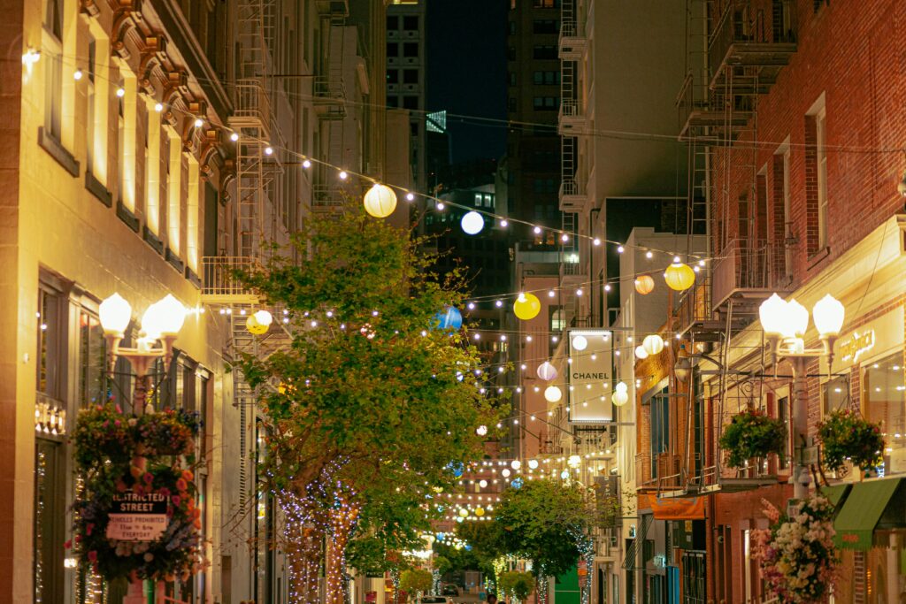 Illuminated street in San Francisco with cafe lights and historic architecture.