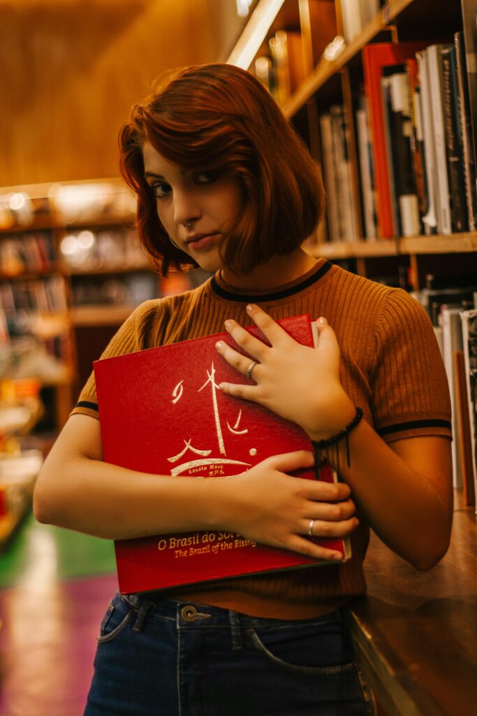 Portrait of a young woman holding a book in a São Paulo library, Brazil.