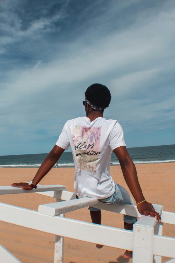 Enjoying solitude, a man sits on a wooden railing overlooking Ocean City's beach.