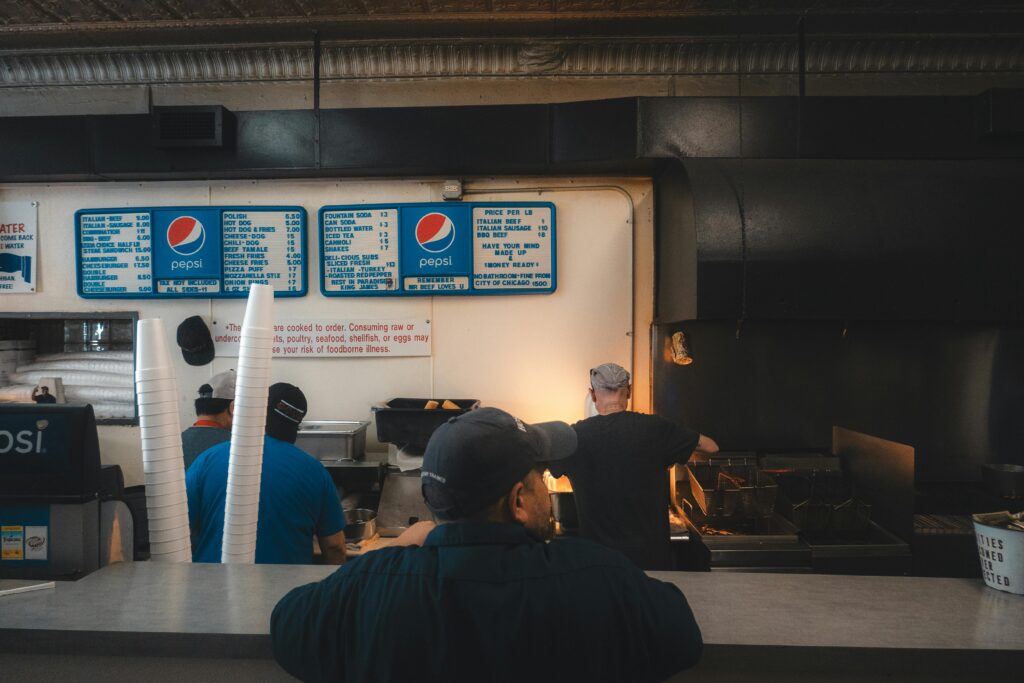 A bustling fast food kitchen with workers preparing meals beneath warm, inviting lighting.