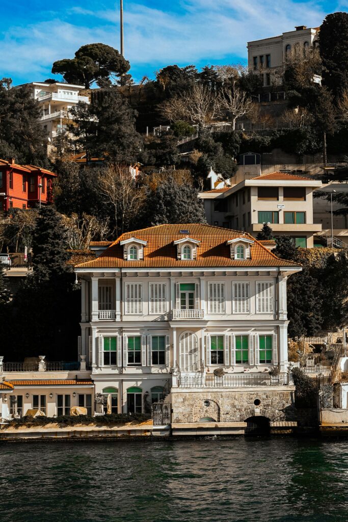 A stunning villa by the waterfront, surrounded by lush hillside architecture.
