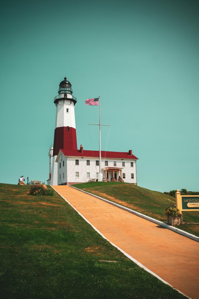 Montauk Point Lighthouse on a sunny day with an American flag waving.