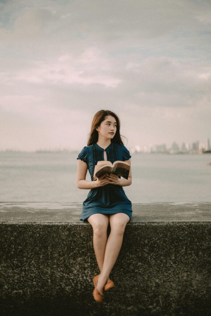 Young woman reading by Manila Bay, enjoying a tranquil sunset at the oceanfront.