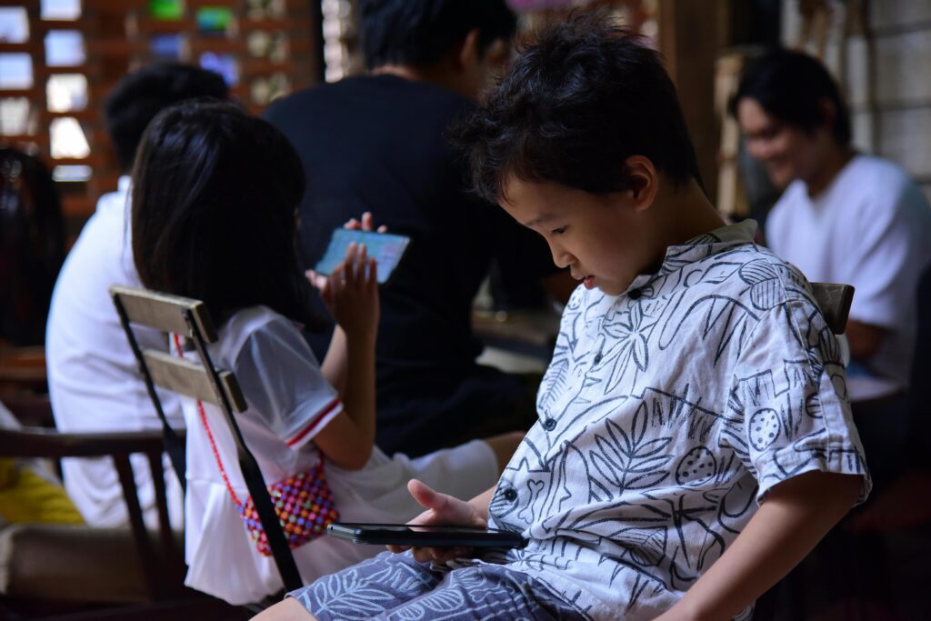 Children focused on smartphones indoors, highlighting contemporary digital lifestyle.