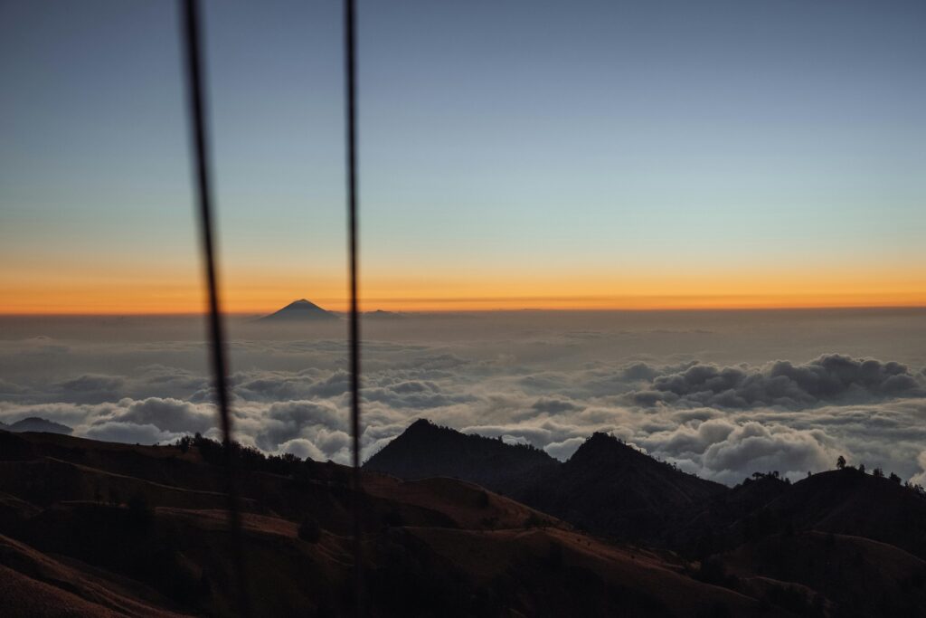 A breathtaking sunrise view over Mount Rinjani with vibrant clouds and clear blue sky, captured from West Nusa Tenggara.
