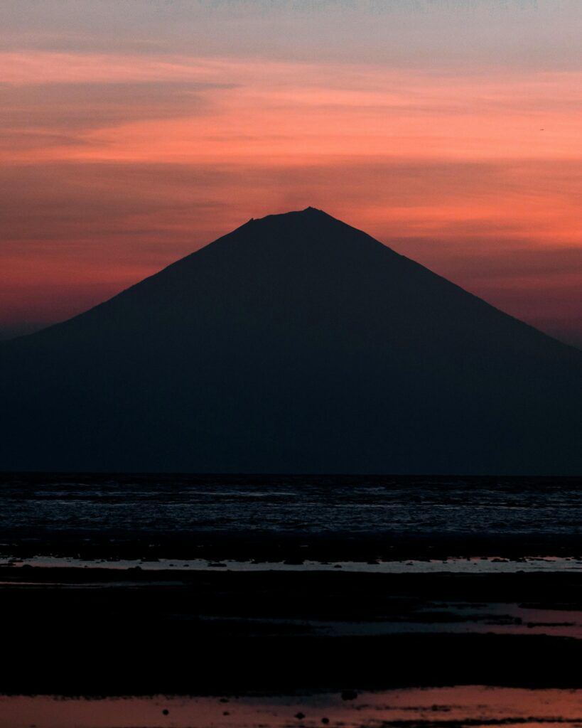 Captivating silhouette of Mount Rinjani against a vibrant sunset sky in West Nusa Tenggara, Indonesia.