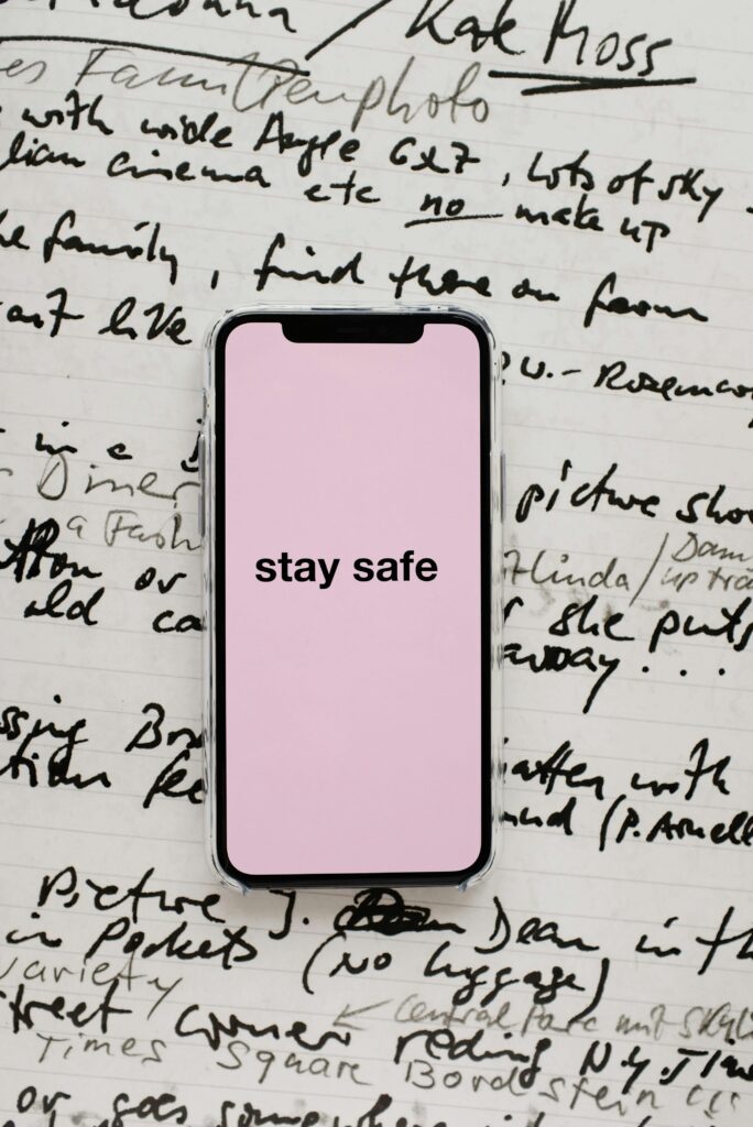 Close-up of a smartphone with 'stay safe' message over handwritten notes, conveying precaution.
