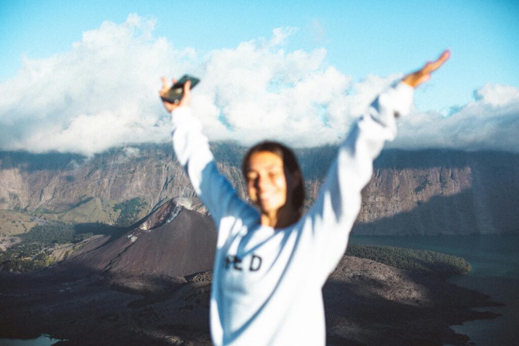 A smiling woman enjoying the stunning view of Mount Rinjani's crater on a sunny day.