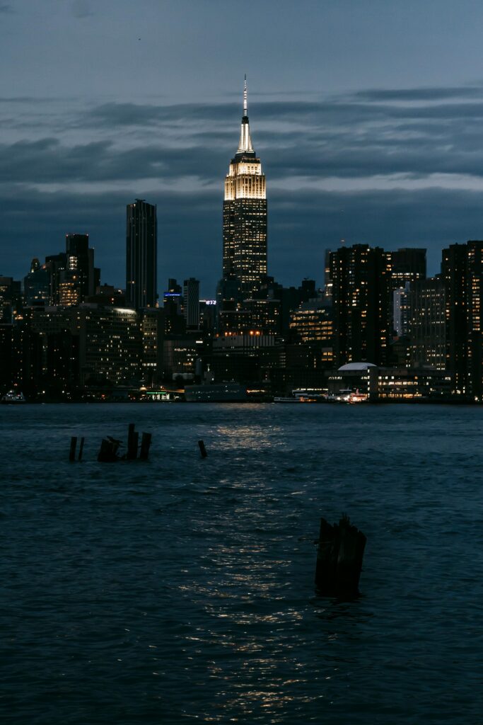 Iconic New York City skyline view with the Empire State Building illuminated at night across the river.