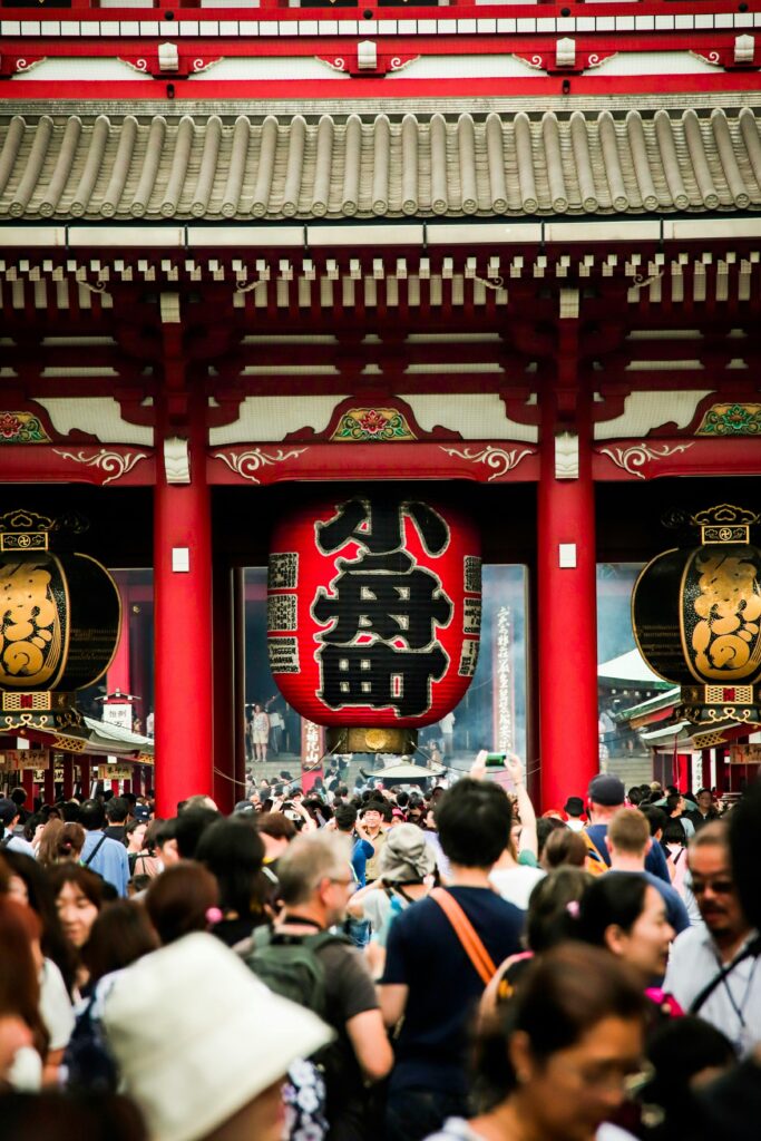 A bustling crowd in front of the historic Senso-ji Temple in Tokyo, Japan, with iconic lanterns.