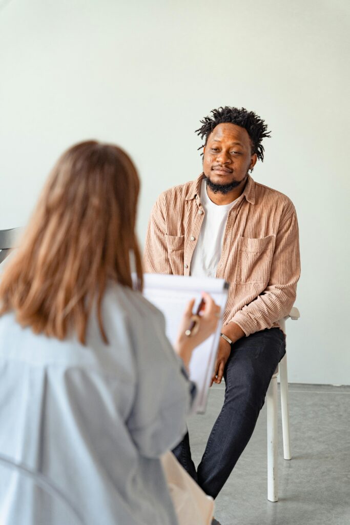 A psychotherapy session between a male patient and a female counselor discussing mental health.