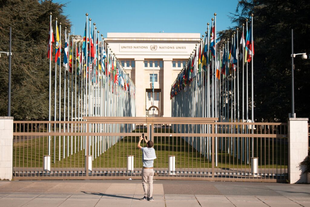 Man photographs the United Nations Office with international flags in Geneva, Switzerland.