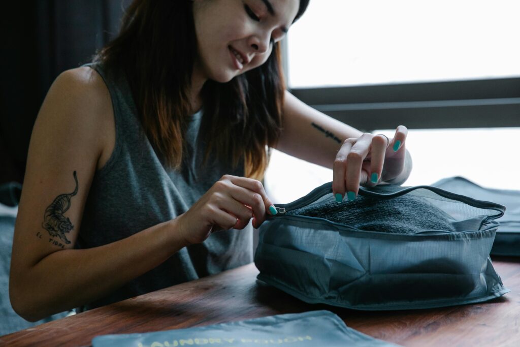 Woman smiling as she zips a travel organizer indoors, preparing for a trip.