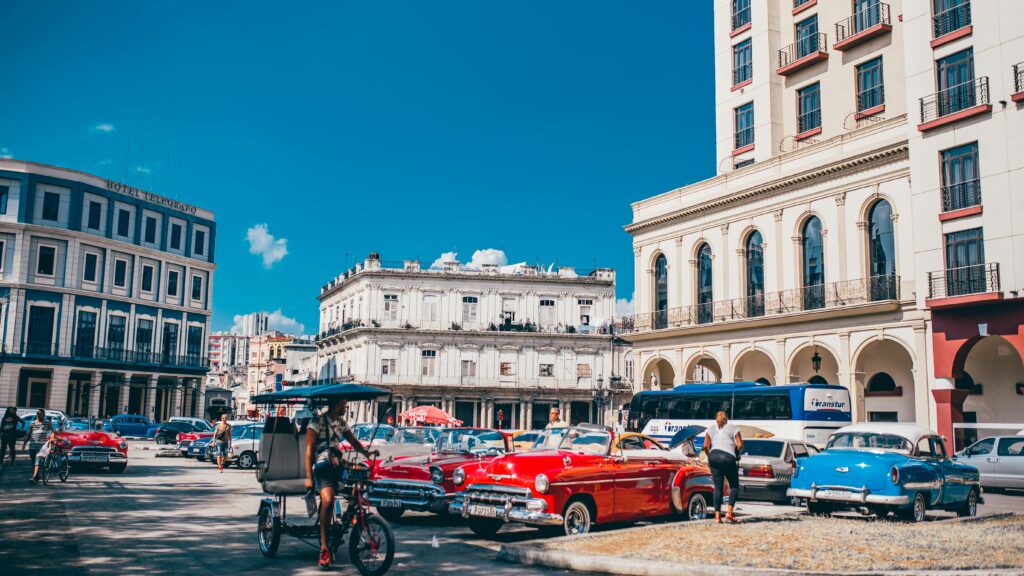 Classic vintage cars against historic Havana architecture under a clear blue sky.