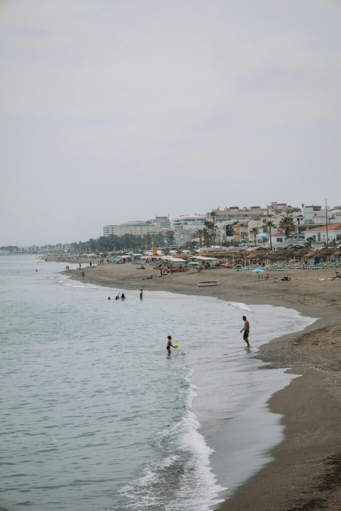A serene view of Málaga's coastal beach on an overcast day, capturing the blend of nature and urban life.