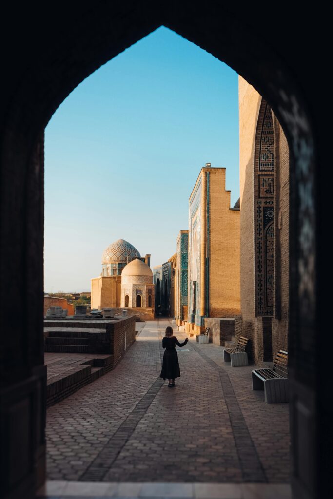 A woman walks through the ancient architectural marvels of Samarqand, Uzbekistan, during the day.