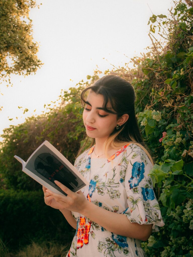 a cute Girl Setting in a garden reading a book