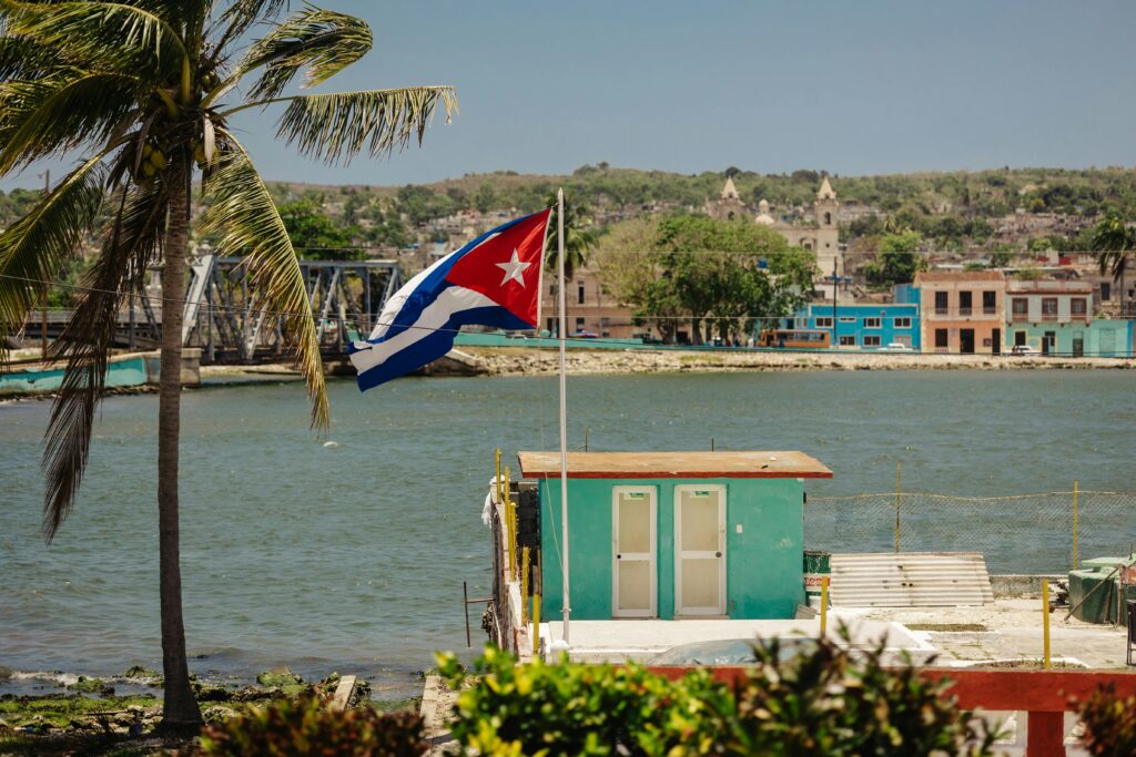 Colorful waterfront view with Cuban flag in Matanzas, Cuba under a bright sky.