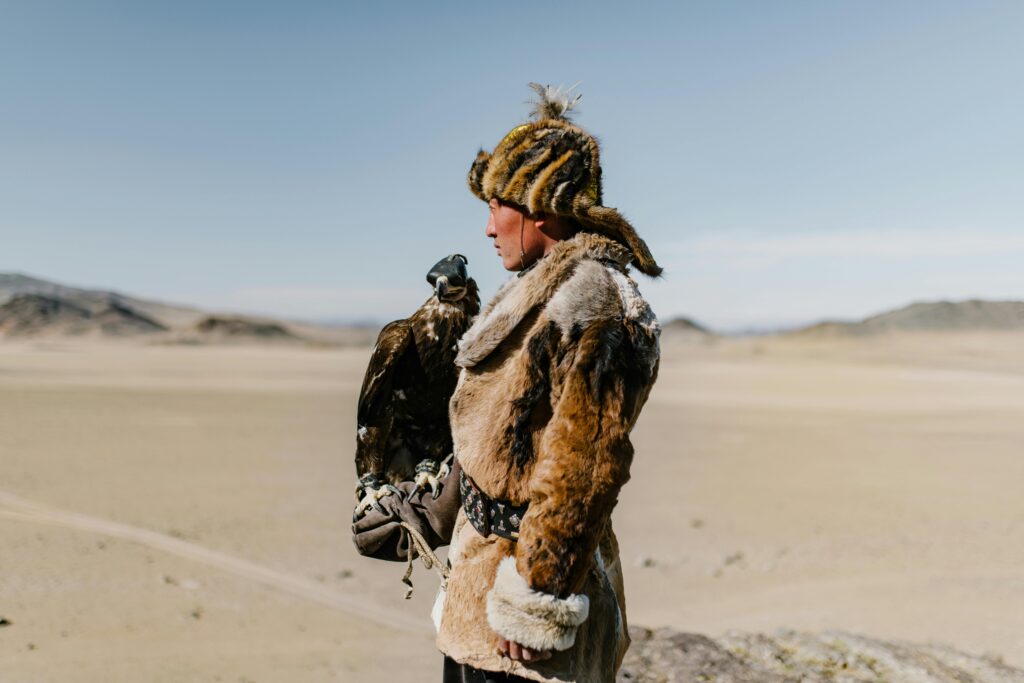 A Mongolian hunter with an eagle in the desert, showcasing traditional falconry skills.