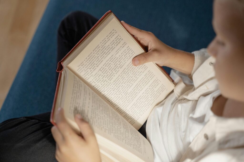 A young child reading a book comfortably indoors, evoking a warm and educational atmosphere.