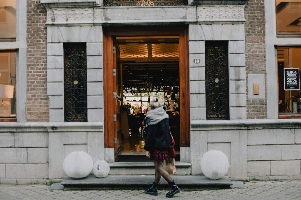 A woman enters a stylish storefront in Maastricht, Netherlands, showcasing urban shopping lifestyle.