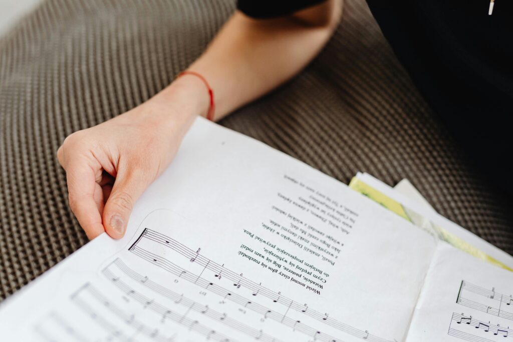 Close-up of a hand holding a sheet music on a textured sofa, focusing on musical notes.