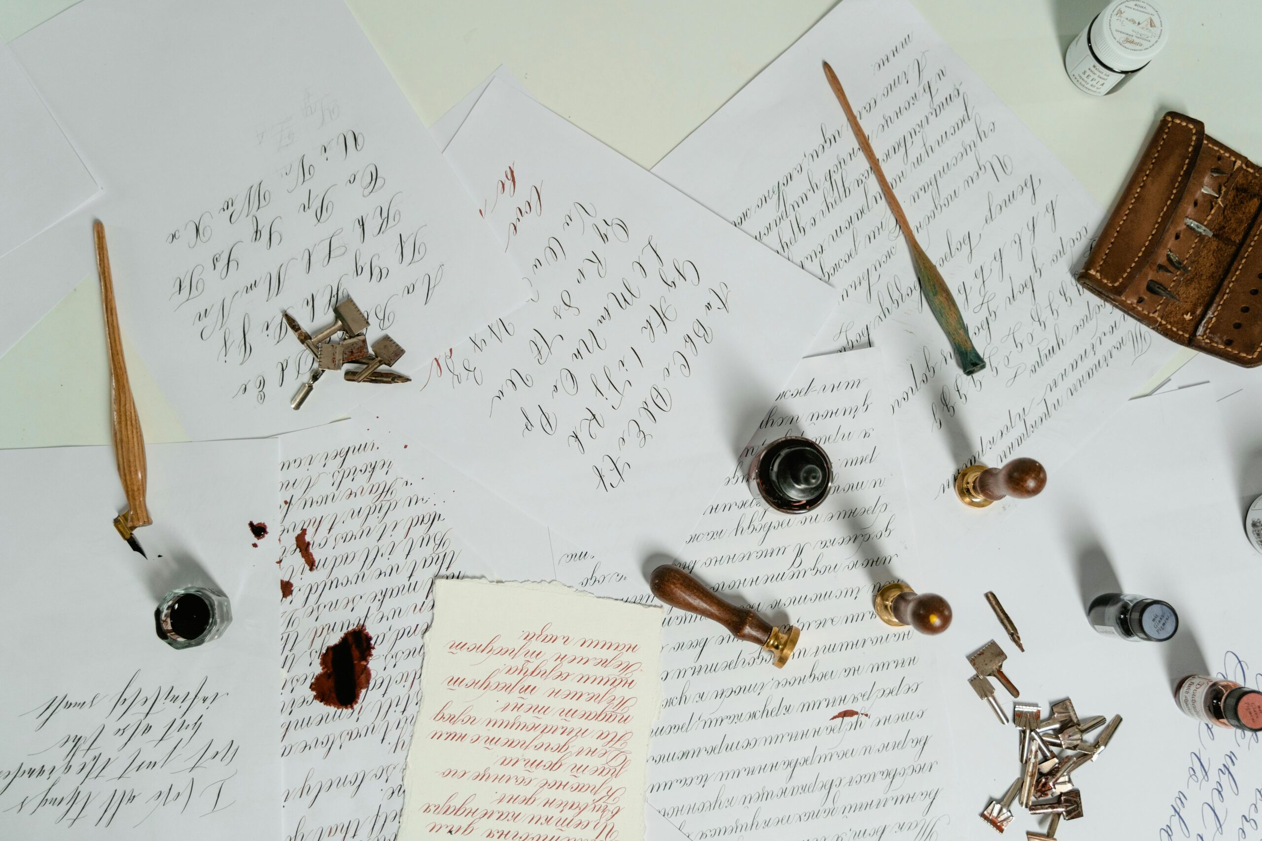 Aesthetic calligraphy arrangement with ink, pens, and handwritten letters on paper.