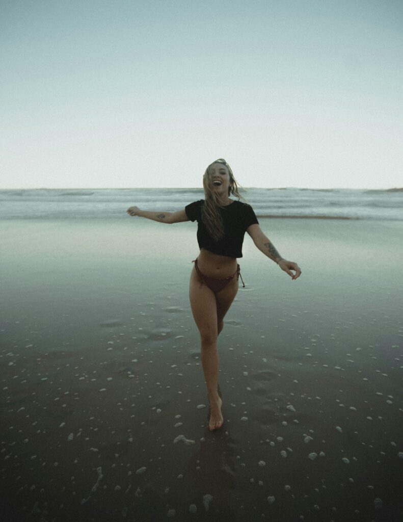 A joyful woman with blond hair running at the beach, expressing freedom and happiness.