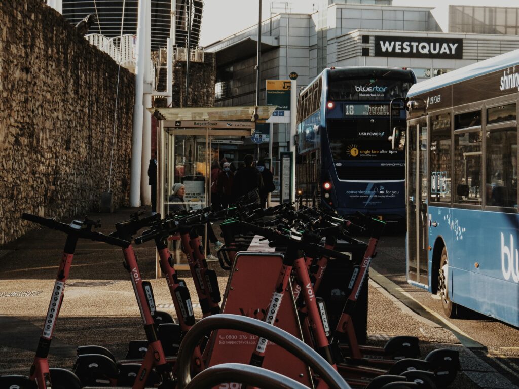 Bustling bus stop with electric scooters and buses near Westquay, England.